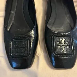 Tory Burch Black Flats with Embossed Logo and Glossy Finish